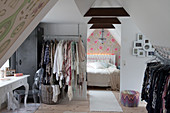Clothes rails in attic room with open doorway leading into bedroom