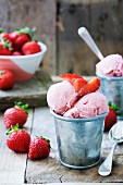 Strawberry ice cream in a small metal bucket with fresh strawberries