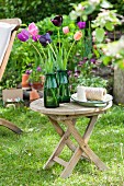 Grüne Glasvasen mit Tulpen auf Gartentisch