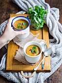 Vegan vegetable cream soup in two cups on a wooden background.