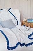 Grey and white patterned blanket with blue crocheted trim
