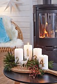 Advent candles with pine sprigs on a wooden board in front of a wood-burning kiln