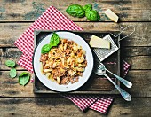 Tagliatelle Bolognese with Parmesan cheese and fresh basil in wooden tray over rustic wooden background