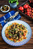 Vegan aubergine meatballs on a bed of spaghetti with tomato sauce and olives