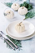 Holiday table setting decoration with white decorative pumpkins, thuja branches and dinner plates