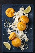 Orangen-Zitronen-Macarons mit weißen Schokoladenspänen auf dunklem Untergrund