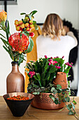 Ornamental apples and needle protea in a vase and Christmas cacti in a decorative bowl