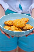 A woman holding a bowl of cheese and chorizo turnovers