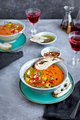 Roasted Tomato Herb Soup topped with cherry tomatoes and basil, served in ceramic bowls served with rose wine, bread and olive oil