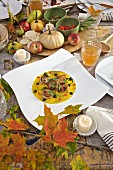 Seared scallops in saffron sauce with truffles, in white plate on country table with pumpkins apples and fall leaves