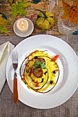 Seared scallops in saffron sauce with truffles on white plates on country table, with a candle and fall decorations