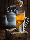 Cup of hot winter spiced tea with honey on a rustic background