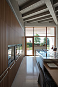 Designerküche mit Einbaugeräten und Mittelblock, im Hintergrund Terrassenzugang