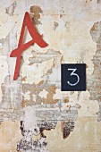 Letters and number on wall with layers of peeling paint