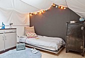Teenager's bedroom with white awning and fairy lights over bed