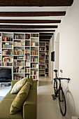 Bicycle behind sofa in living room with large bookcase