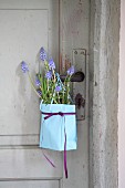Paper bag of grape hyacinths and rosemary hung from door