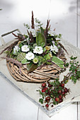 Wreath decorated with white asters, thistles and poppy seedheads next to posy of rose hips