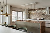 Kitchen island with marble worktop and geometric wall tiles in elegant, open-plan kitchen
