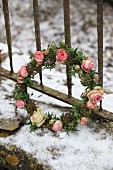 Romantischer Blütenkranz mit Rosenblüten und Efeublättern im Schnee