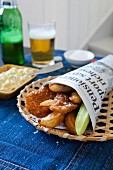 Breaded chicken strips with french fries in newspaper bag