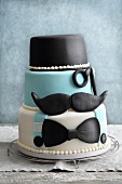A three-tier fondant icing 'Movember' cake with moustaches