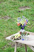 Arrangement of cottage-garden flowers on table on lawn
