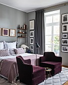 Two purple velvet armchairs at foot of bed in glamorous bedroom