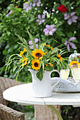 Sonnenblumen mit Ziergras in Krugvase auf Gartentisch