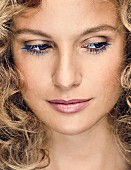 A blonde woman with curly hair and blue eyelashes