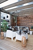 White outdoor armchairs in comfortable lounge area on roofed wooden terrace