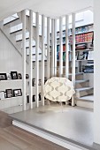 Podest mit Designerleuchte vor eingebautem Bücherregal im Treppenaufgang