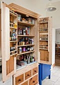 Stripped wooden cupboard with multiple spice racks on inside of doors