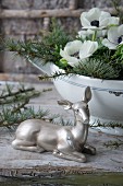 Silver doe ornament in front of arrangement of larch twigs and anemones in soup tureen