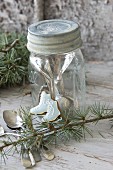 Ice-skate-shaped iced biscuit leaning against screw-top jar with silver cutlery inside