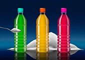 Row of brightly colored soft drink bottles and pile of sugar