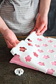 A sheet of fondant icing with cut-out flowers for a cake board