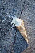 An ice cream cone on asphalt (top view)