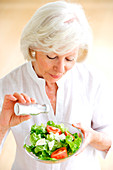 Woman adding salt on a salad