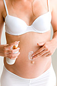 Pregnant woman applying cream