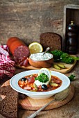 Solyanka (Traditional Russian meat soup from different kinds of meat and sausages with pickled cucumber and lemon)