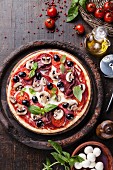 Italian pizza with salami, mushrooms and olives on wooden table