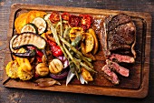 Club-Steak mit Pfeffersauce und Gemüse vom Grill auf Holzbrett