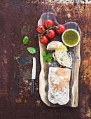 Freshly baked ciabatta bread with cherry-tomatoes, olive oil, basil and salt on walnut wood board