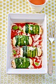 Zucchini rolls with fresh cheese filling on tomato sauce