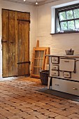 Old, wood-burning kitchen stove on rustic floor made of wooden tiles