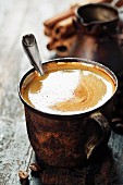 Kaffee mit Löffel in Vintage Becher auf rustikalem Untergrund