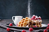 Belgian waffles with raspberries and sieving sugar powder, served with jug of milk