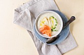 Bowl of white asparagus cream soup with pea sprouts, salted salmon and toast