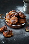 Apple dough fritters with powdered sugar on a dark background